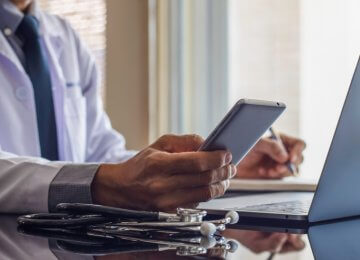 A doctor using a phone and a laptop