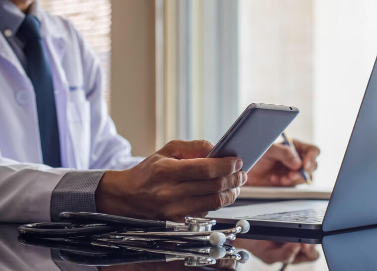 A doctor using a phone and a laptop